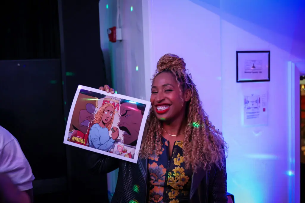 Frankey Smith smiles while holding an illustrated print of herself in an Invincible-inspired scene at the creator screening event.