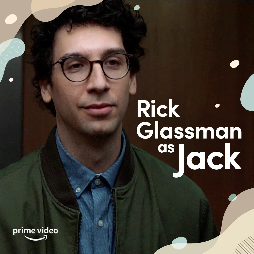 Close-up portrait of Rick Glassman as Jack wearing round glasses, blue shirt and olive jacket against a dark background, with large white title text 'Rick Glassman as Jack' and Prime Video logo.