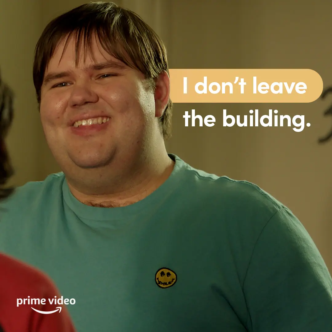 Smiling young man in a teal T-shirt fills the left side as a rounded yellow callout on the right reads, "I don't leave the building." Prime Video logo sits in the lower corner.