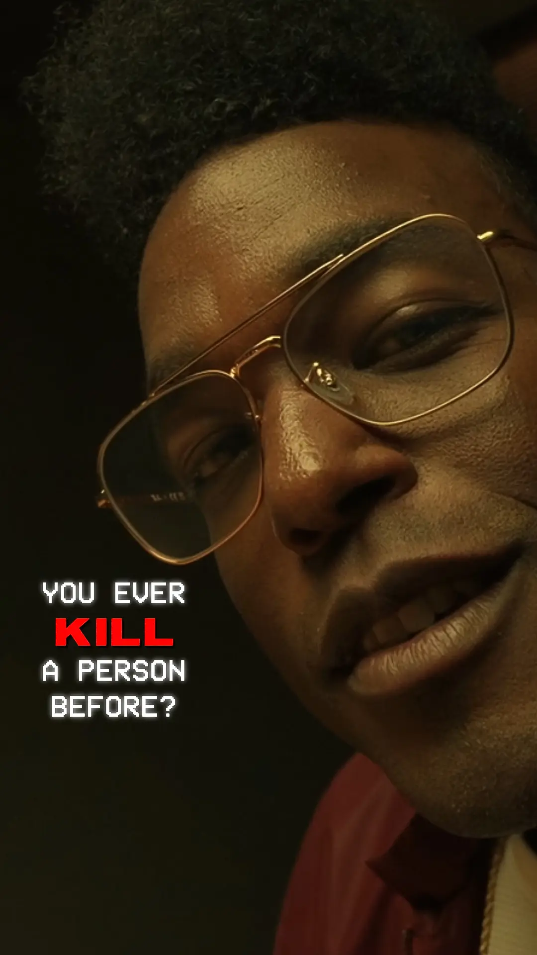Close-up portrait of Edmund Gaines wearing gold-rimmed glasses, slight smile against a dark background with white text asking 'YOU EVER KILL A PERSON BEFORE?' and the word 'KILL' highlighted in red.