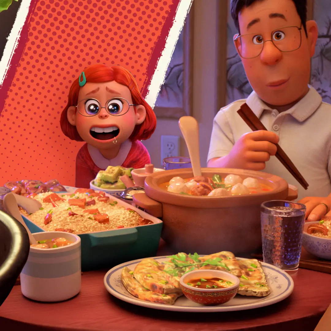 Young red-haired girl with glasses looks wide-eyed across a crowded family dinner table as an adult man beside her holds chopsticks and several steaming dishes sit in the foreground.