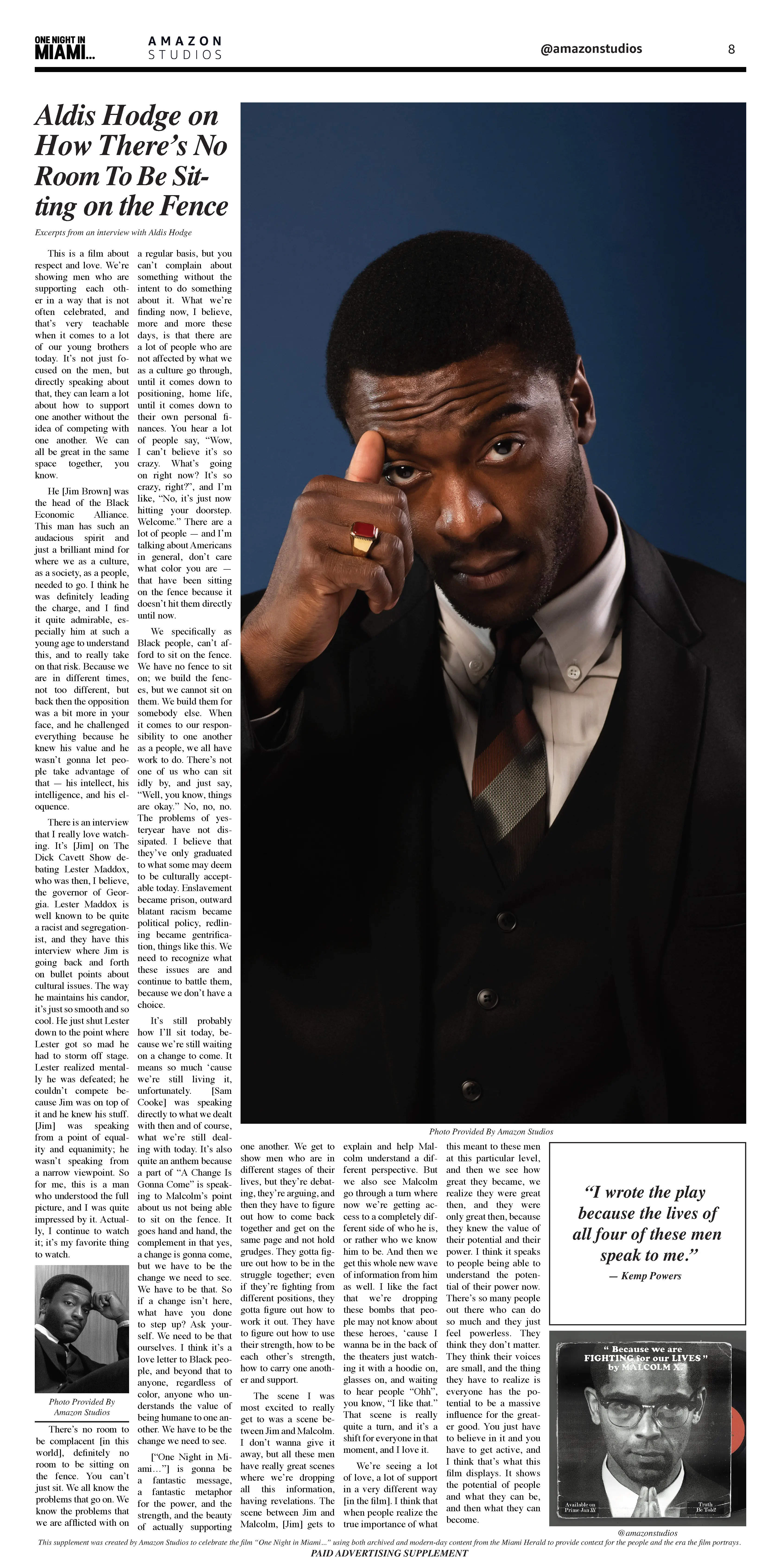 A three-quarter portrait of Aldis Hodge in a dark suit against a deep blue background, hand raised near his face showing a signet ring, with a broadsheet-style text column at left.