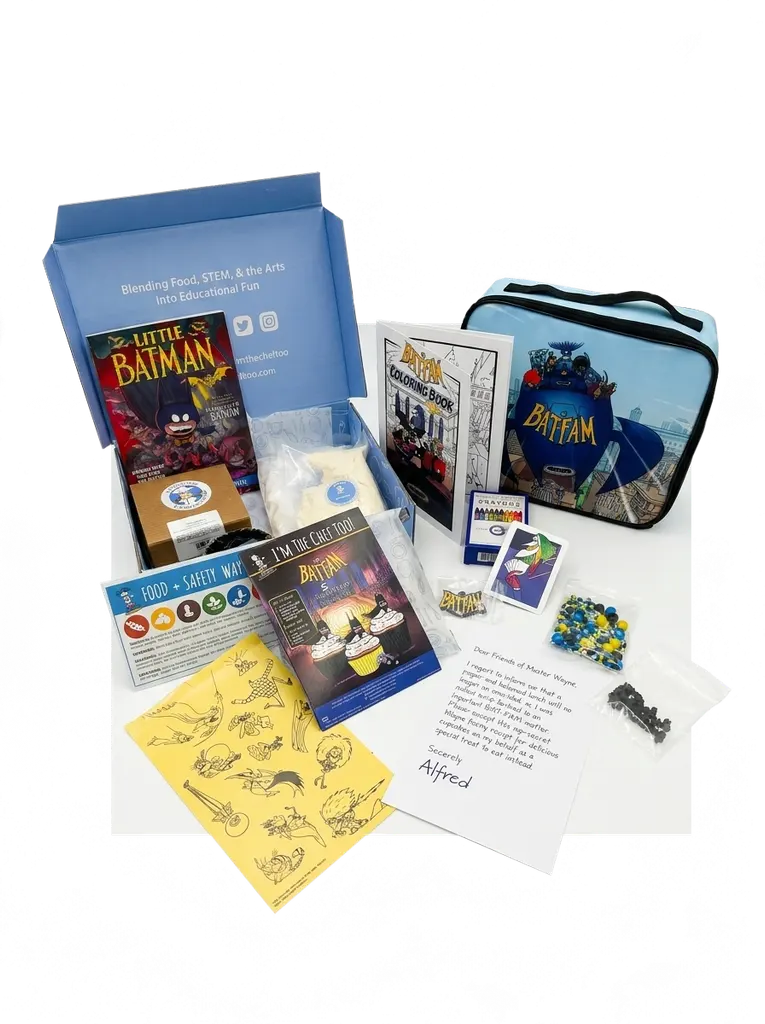 Open Bat-Fam influencer kit arranged on a white surface showing a branded blue box, BatFam lunchbox, coloring book, recipe booklet, sticker sheets, card pack, bagged sprinkles and chocolate, and an Alfred note.